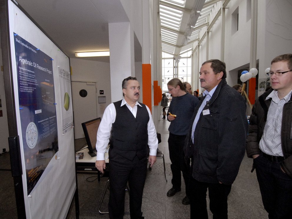 Prof. Kreuzer erklärt den Besuchern der Ausstellung das algebraic oil research project